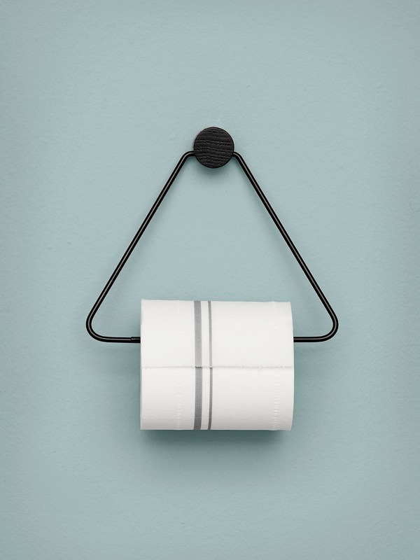 Zwarte Ferm Living toiletrolhouder Scandinavisch design hangend op een blauwe muur. Strakke en minimalistisch ontwerp voor de badkamer of wc