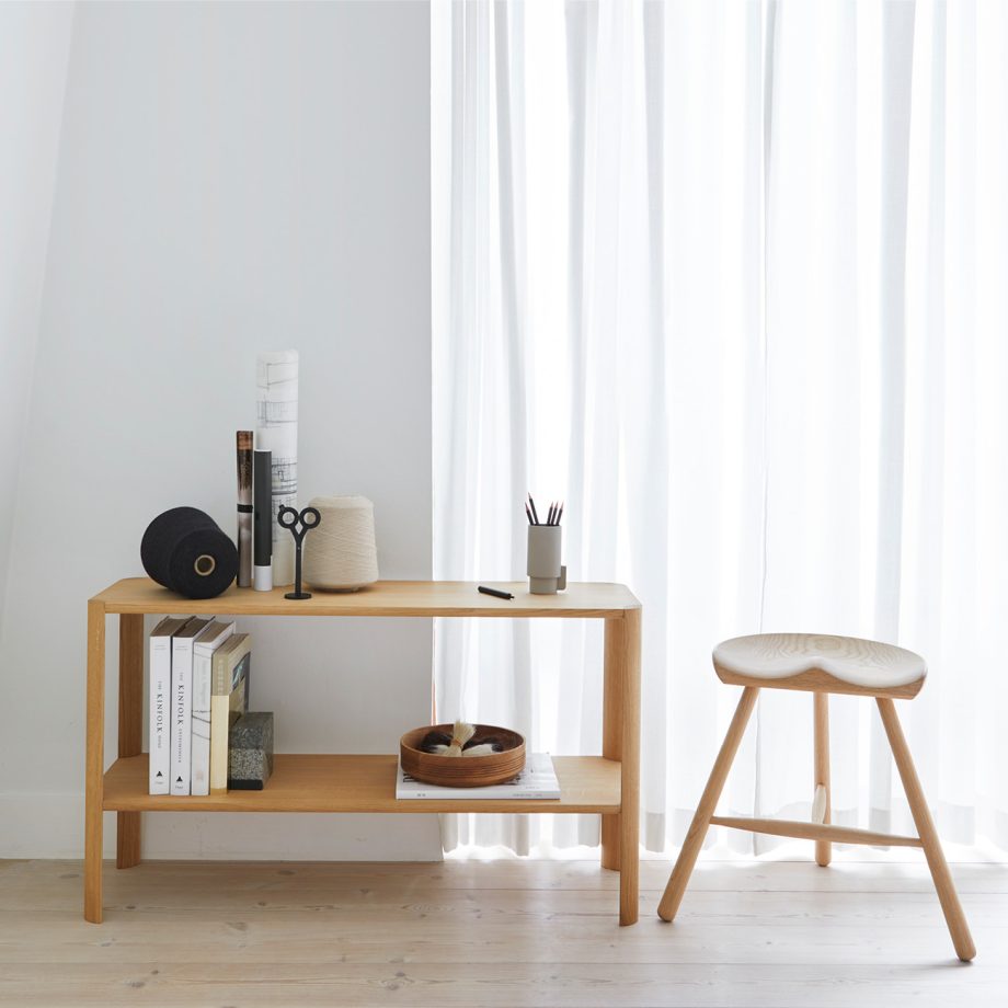 Form & Refine Leaf kast in wit eikenhout, minimalistisch gestyled met boeken, decoratieve objecten en een bijpassende houten kruk in een licht en modern interieur.