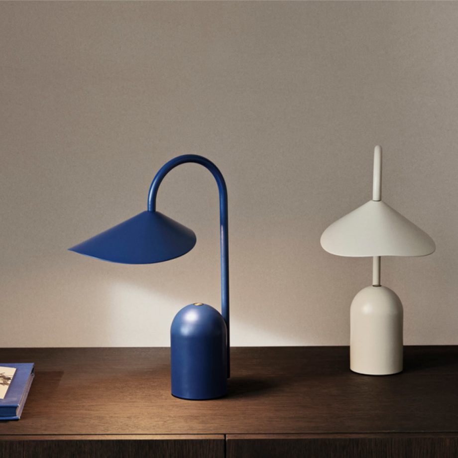 De Ferm Living Arum Portable Lamp in blauw en crème kleuren, stijlvol gepresenteerd op een houten dressoir, ideaal voor sfeerverlichting en modern interieurdesign