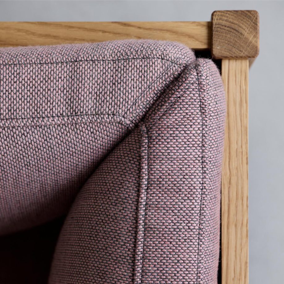 Close-up van de MOEBE modulaire bank met hoogwaardige stoffering in een warme roze tint en een solide massief eikenhouten frame. Het Scandinavische design en de verfijnde afwerking maken deze bank een duurzame en stijlvolle keuze voor elk interieur.