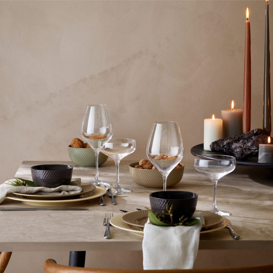 Luxe gedekte eettafel met Lyngby Rhombe servies in warme aardetinten. Luxe porseleinen borden en kommen met elegant reliëf, gecombineerd met stijlvolle wijnglazen en sfeervolle kaarsen voor een verfijnde tafelschikking. Ideaal voor een chique diner of sfeervol samenzijn.
