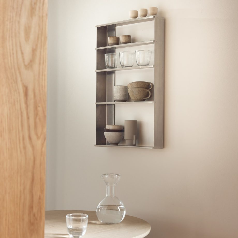 Stijlvolle metalen wandplank met karaf, mokken en keramieken van Form & Refine in een minimalistische eetkamer.