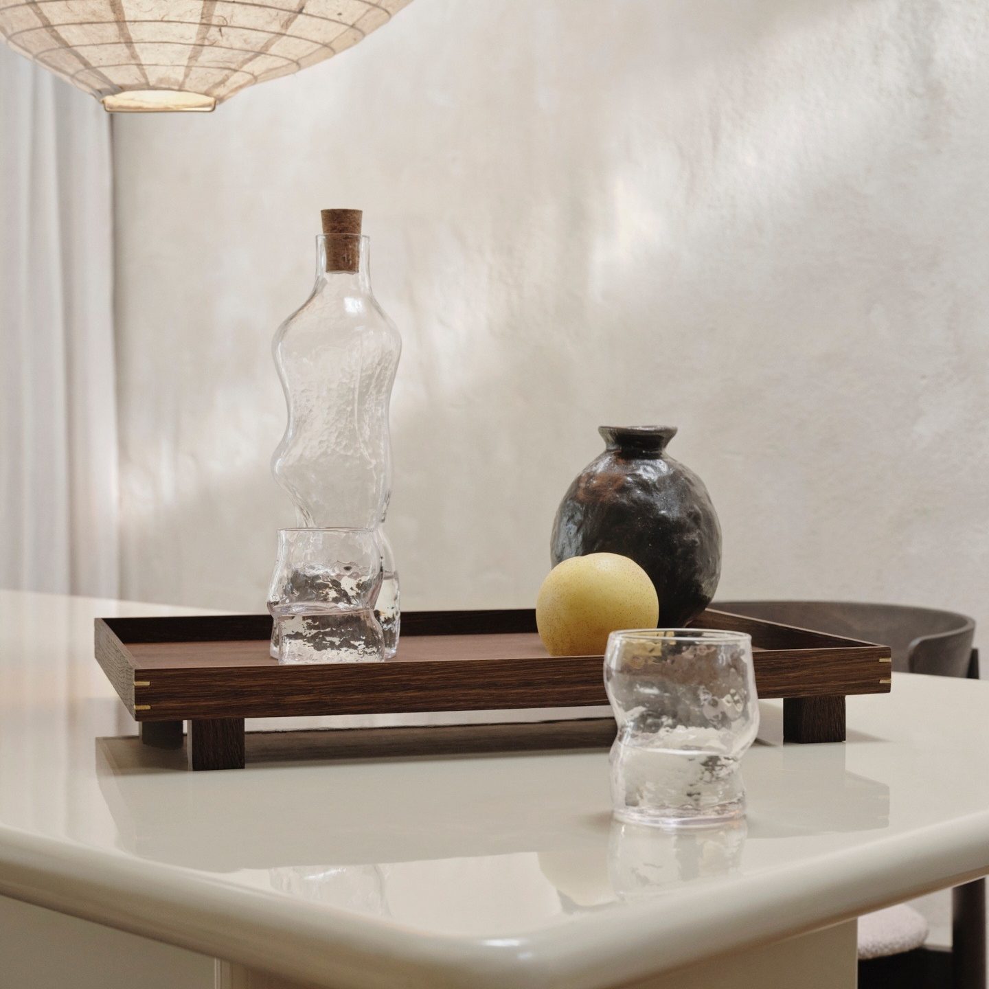 Stijlvolle eettafel met de Bon Wooden Tray in gerookt eiken van ferm LIVING, gecombineerd met een karaf, bijpassende glazen en keramisch vaasje – modern Scandinavisch interieur.