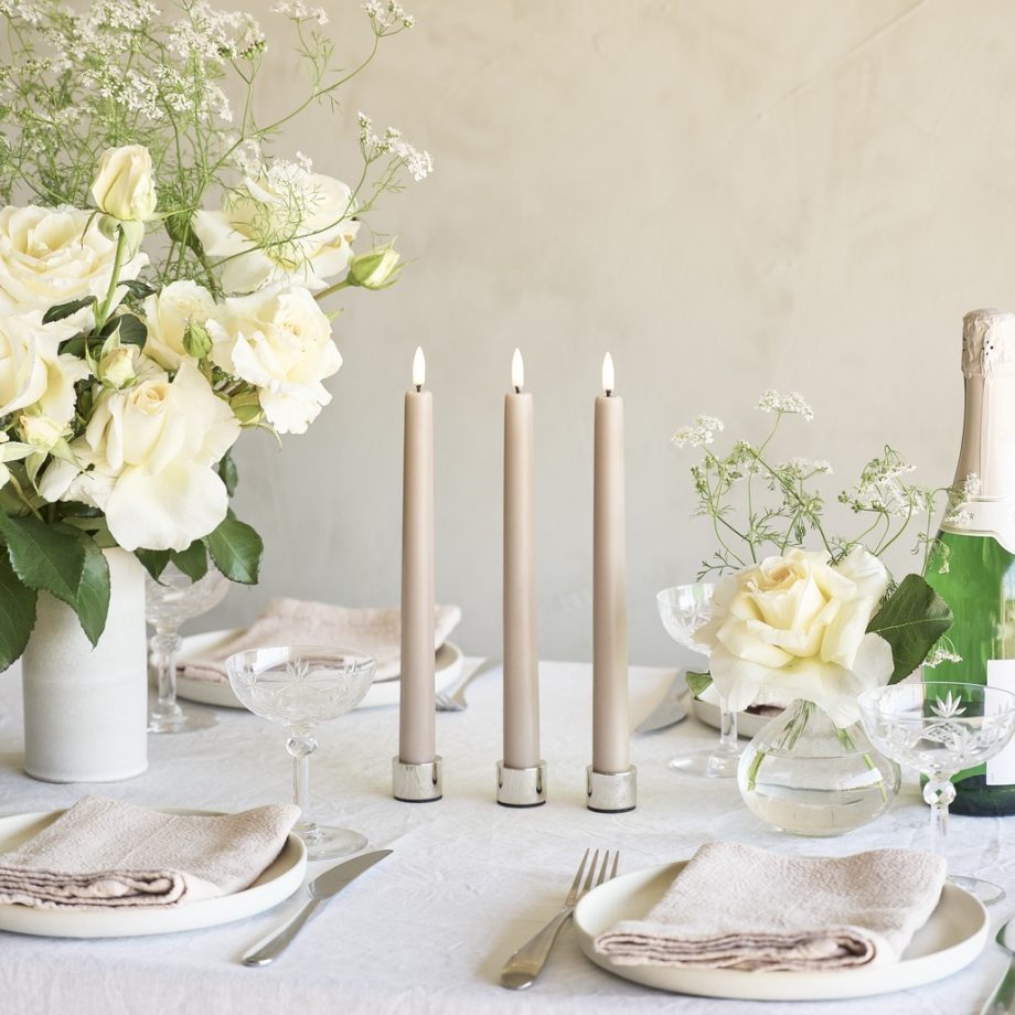 Tafelsetting huwelijk met witte bloemen, servies en beige LED dinerkaarsen in metalen Light kandelaar van Uyuni Lighting