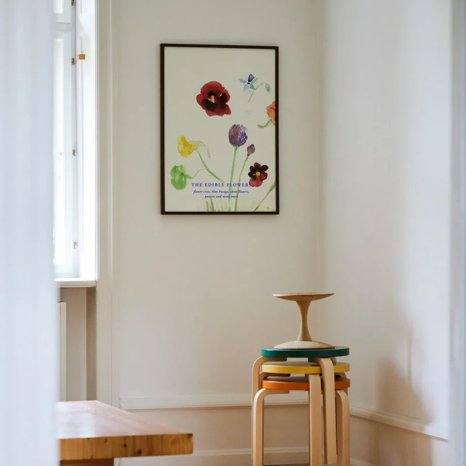 The Edible Flowers poster met kleurrijke bloemen in een zwarte lijst hangend op witte muur in de eetkamer