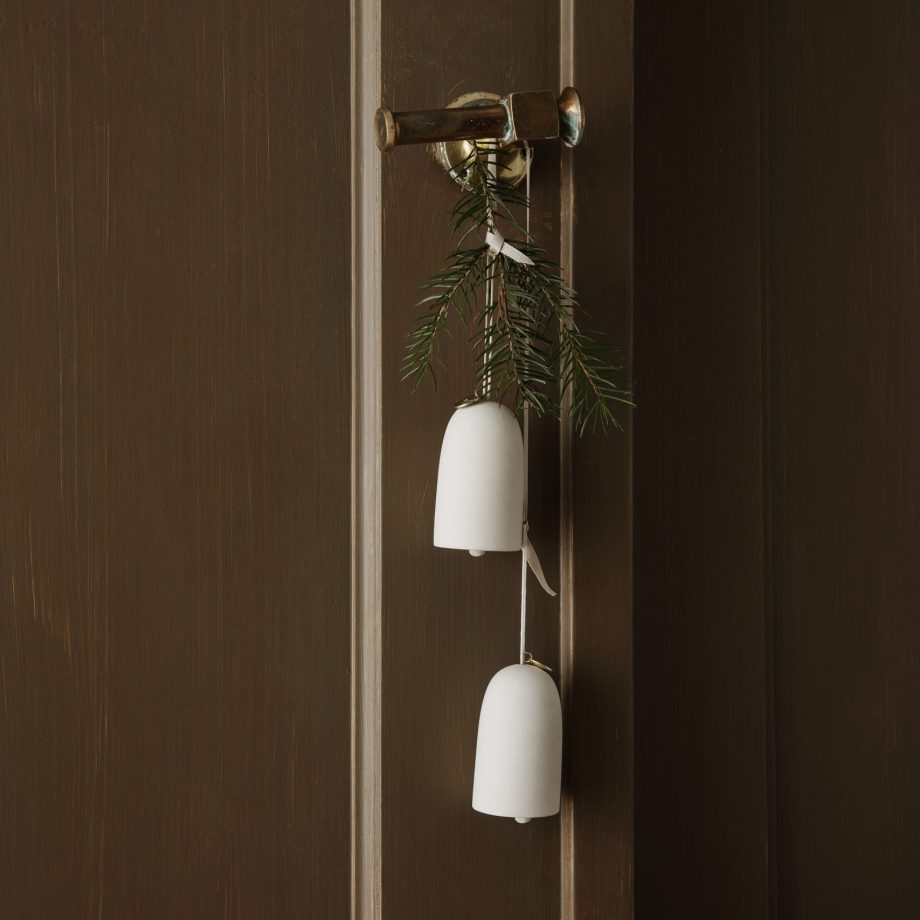 Bell kerstklokken ornamenten van Ferm Living hangend aan een donker muur